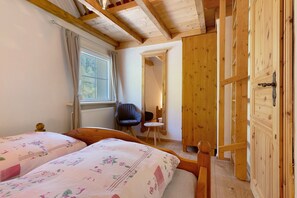 Un dormitorio con dos camas, una ventana, una silla y un armario de madera.