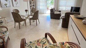 Ein modernes Wohnzimmer mit einem Glastisch, Korbstühlen, einer Couch und einem Fernseher.