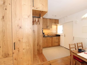 Uma cozinha moderna com armários de madeira, uma área de jantar com mesa e cadeiras, e uma janela que oferece iluminação natural.
