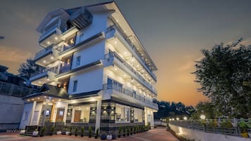 A multi-story hotel with balconies, large windows, and a well-lit entrance.