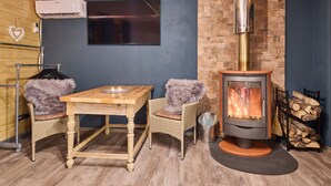 Une pièce chaleureuse avec une table en bois, des chaises, une cheminée et un téléviseur fixé au mur.