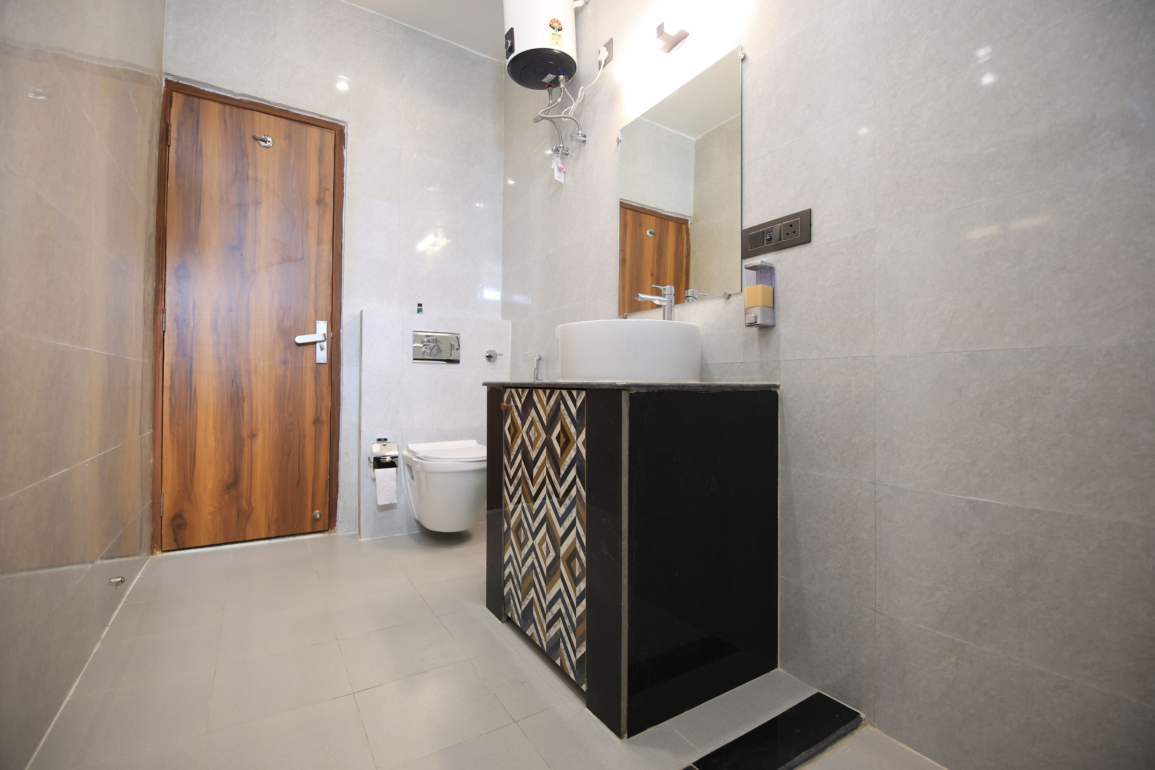 A modern bathroom with a wooden door, a white sink, and a mirror above it.