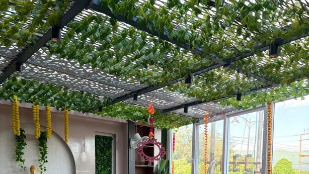 Un restaurant avec des tables et des chaises, une statue de Bouddha et de la verdure.