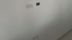 A plain white wall with two electrical outlets and a small black switch.
