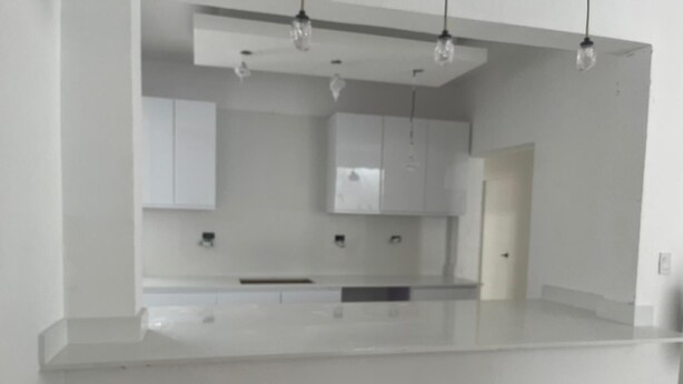A modern kitchen with white cabinets, a central island, and pendant lighting.