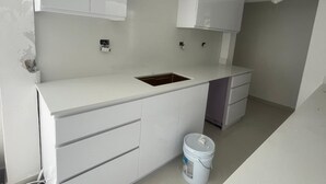 A modern kitchen with white cabinetry, a built-in sink, and a white countertop.