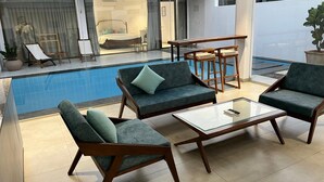 A modern indoor pool area with lounge chairs and a glass coffee table. - Rocks and Greens (Padmanabham)