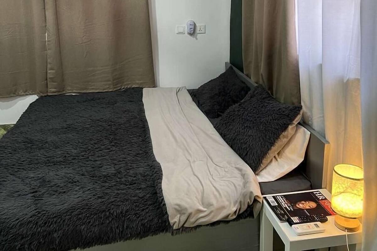 A neatly made bed with a fluffy blanket, a bedside table with a lamp, and a magazine.