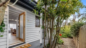 A house with a wooden exterior, a visible entrance, and a garden area with a pathway and plants.