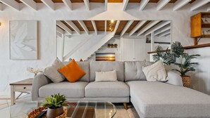 A modern living room with a grey sectional sofa, a glass coffee table, and a staircase leading to an upper level.