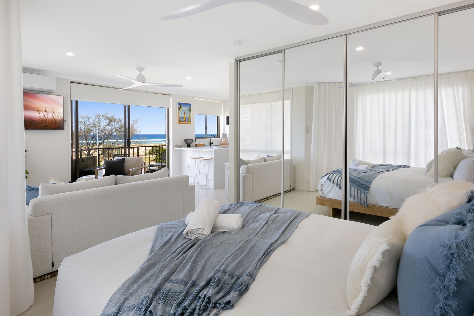 Ein modernes Hotelzimmer mit Bett, einer Sitzecke, einem Balkon mit Blick und einem großen Spiegel.