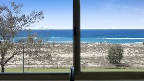 Blick auf einen Strand mit klarem Himmel und Meereswellen.