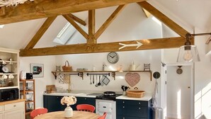 A kitchen with a wooden ceiling, a dining table with red chairs, and a heart-shaped decoration on the wall.