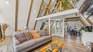 Ein großzügiger Loft-Wohnbereich mit hoher Decke, einer Couch, einem Couchtisch und einem Essbereich.