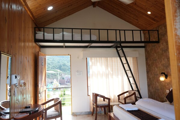 Una habitación con literas, un escritorio con silla, una escalera y vistas al exterior.