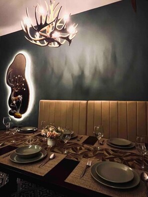 A dining area with a modern chandelier, a unique wall art piece, and a cushioned bench. - Rusa Cottage (Sleeps 10 pax - 1 min walk from KSL) (Johor Bahru)