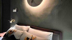 A bedroom with a bed, pillows, and a wall-mounted circular light fixture with a deer silhouette.