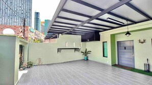 A spacious rooftop terrace with a modern design, featuring a flat roof, a potted plant, and a door with a decorative antler.