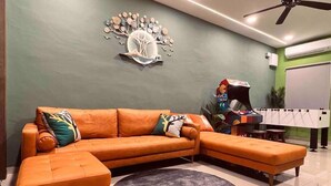 A modern living room with a sectional sofa, a round rug, and a decorative wall piece.