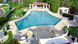 A large, irregularly shaped swimming pool with a covered seating area and lounge chairs around it. - 2Bed/2Bath at the Tennis Village at Palmas del Mar (Humacao)