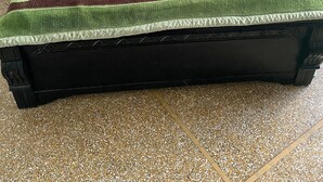 Una cama con colcha estampada con motivos florales y ribete verde al pie.