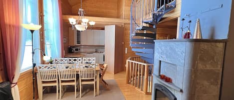 A cozy cabin interior with a dining area, kitchen, and a fireplace.