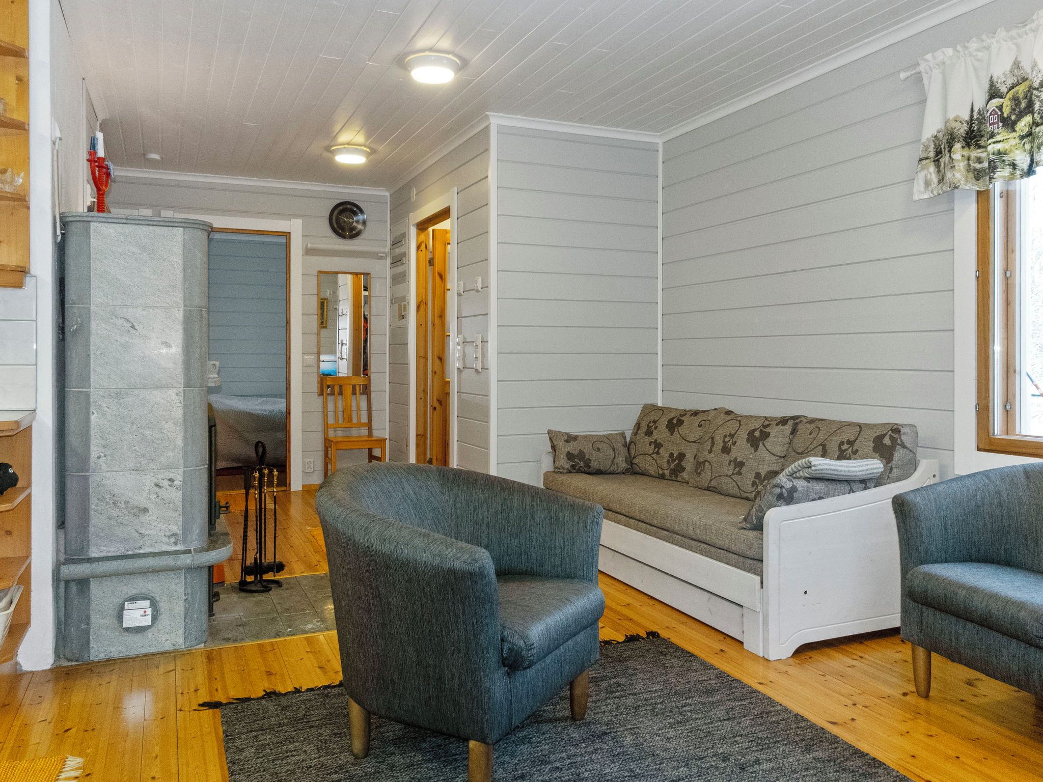A cozy living room with a gray sofa, a blue armchair, and a wooden floor.