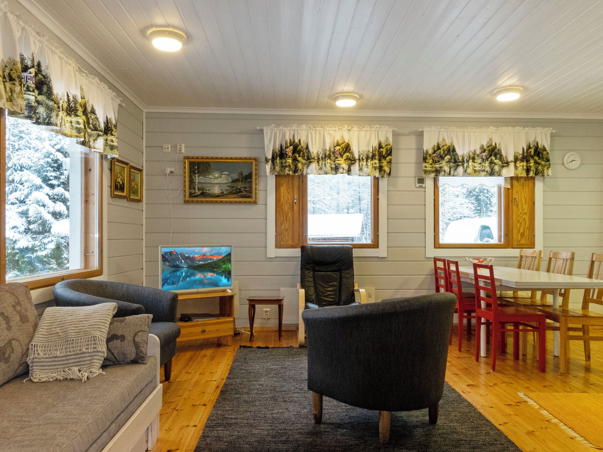 Una sala de estar acogedora con un sofá, un televisor, una mesa de comedor con sillas y una chimenea.