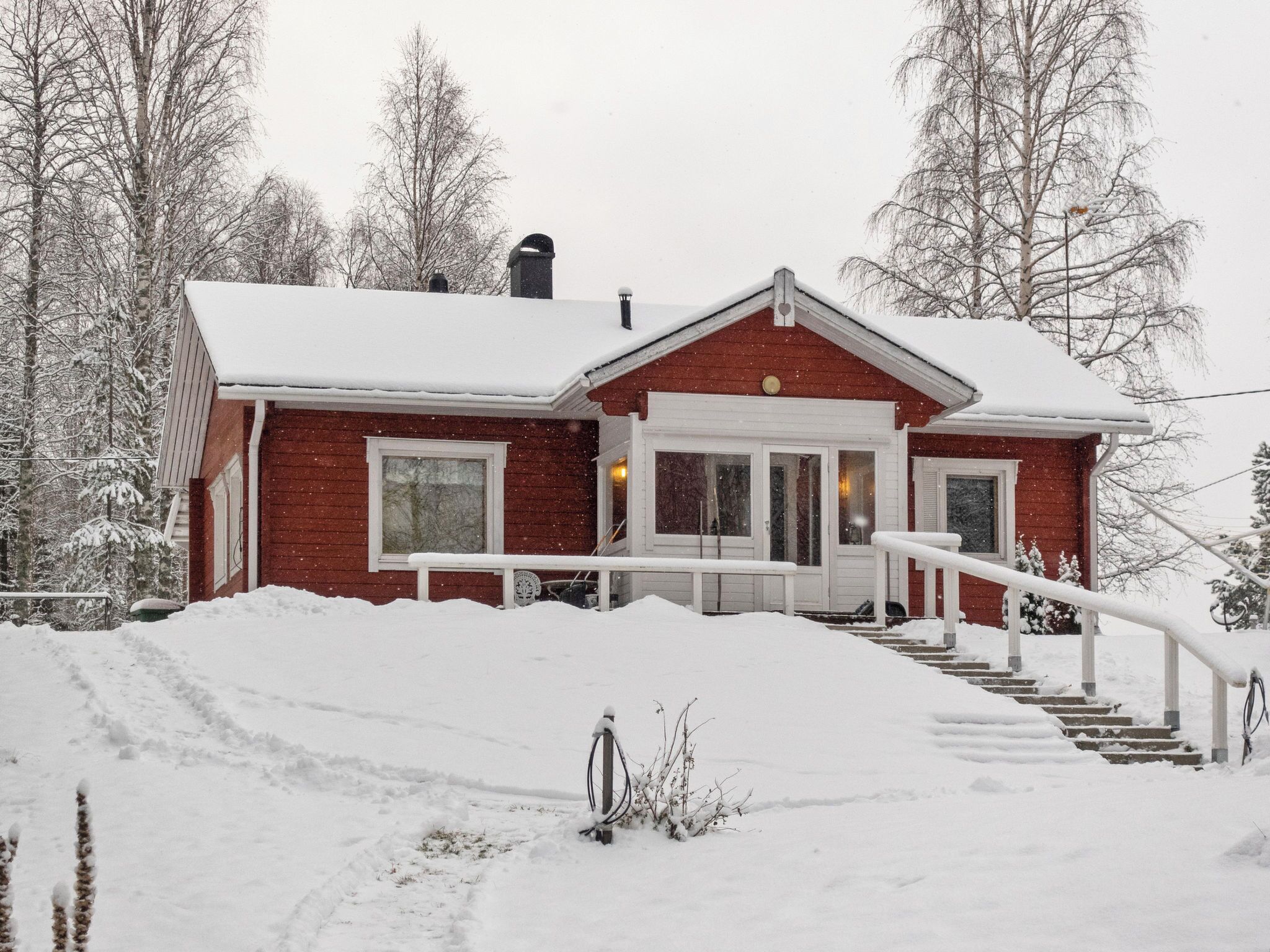 A red house with a white porch and steps leading up to the front door.