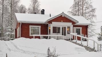A red house with a white porch and steps leading up to the front door.