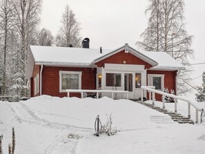 A red house with a white porch and steps leading up to the front door.