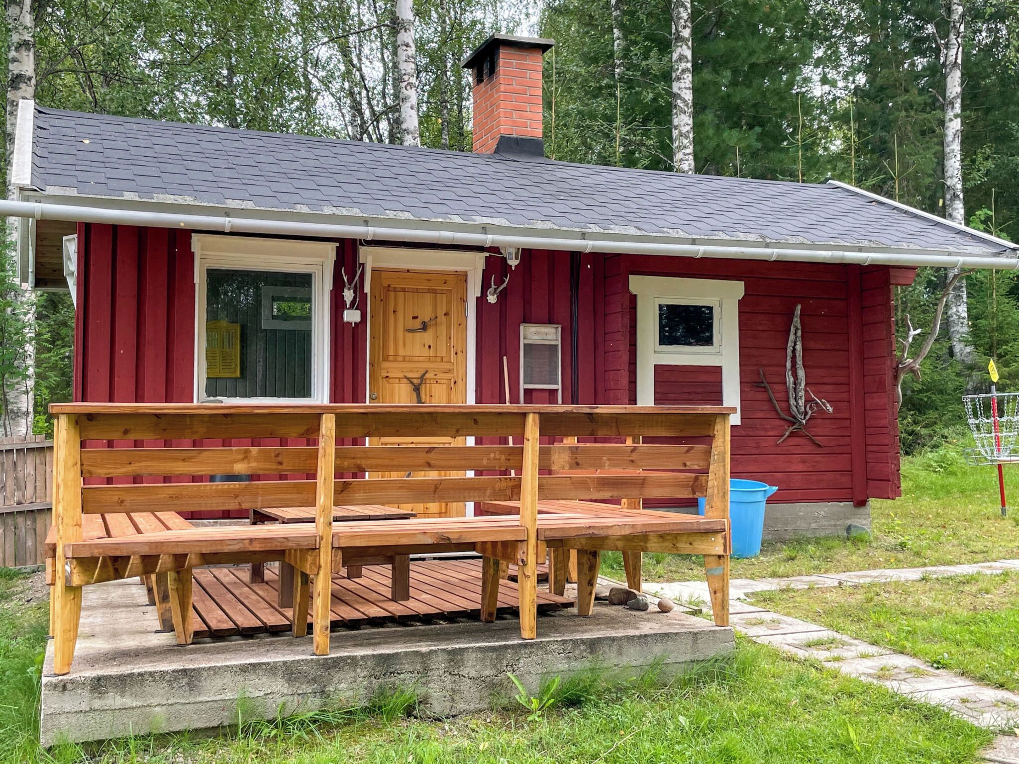 A red wooden cabin with a porch and a chimney.