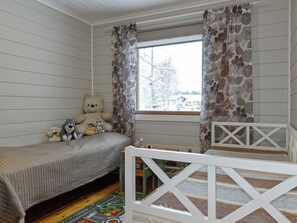 A child's bedroom with a bed, a small table, and a window with curtains.
