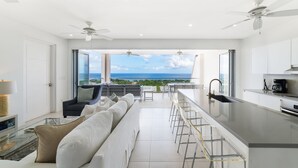 A modern kitchen with a large island, a dining area with a view, and a seating area with a sofa and chairs. - White 4 bedroom villa with amazing ocean views in a gated community in St James (Fitts Village)
