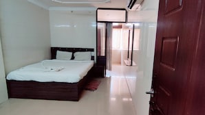 A hotel room with a bed, a wooden headboard, a tiled floor, and a door. - PPH Living EDEN PARK HOTEL INDIRA NAGAR (Bengaluru)