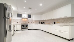 Une cuisine moderne avec des meubles blancs, un four encastré et un réfrigérateur en acier inoxydable.