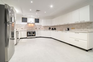 A modern kitchen with white cabinetry, a built-in oven, and a stainless steel refrigerator.