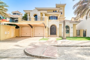 A large, two-story house with a garage, a balcony, and a well-maintained lawn.