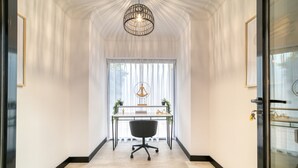 Un couloir avec un bureau, une chaise et un luminaire suspendu.