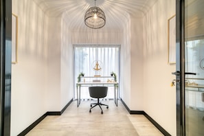 A hallway with a desk, chair, and pendant light.
