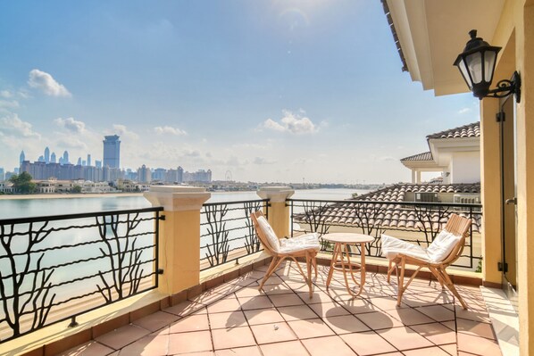 A balcony with a view of a city skyline across a body of water.