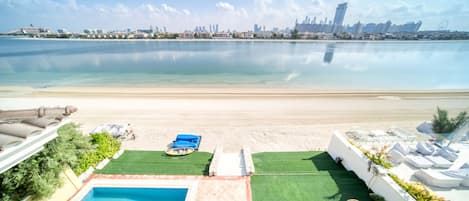 A pool area with a view of a beach and city skyline.
