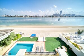 A pool area with a view of a beach and city skyline.