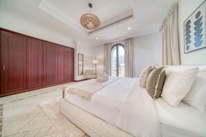 Un dormitorio con una cama grande, un armario, una ventana con cortinas y una lámpara en el techo.