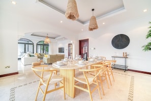 A spacious dining area with a round table set for six, surrounded by wooden chairs.