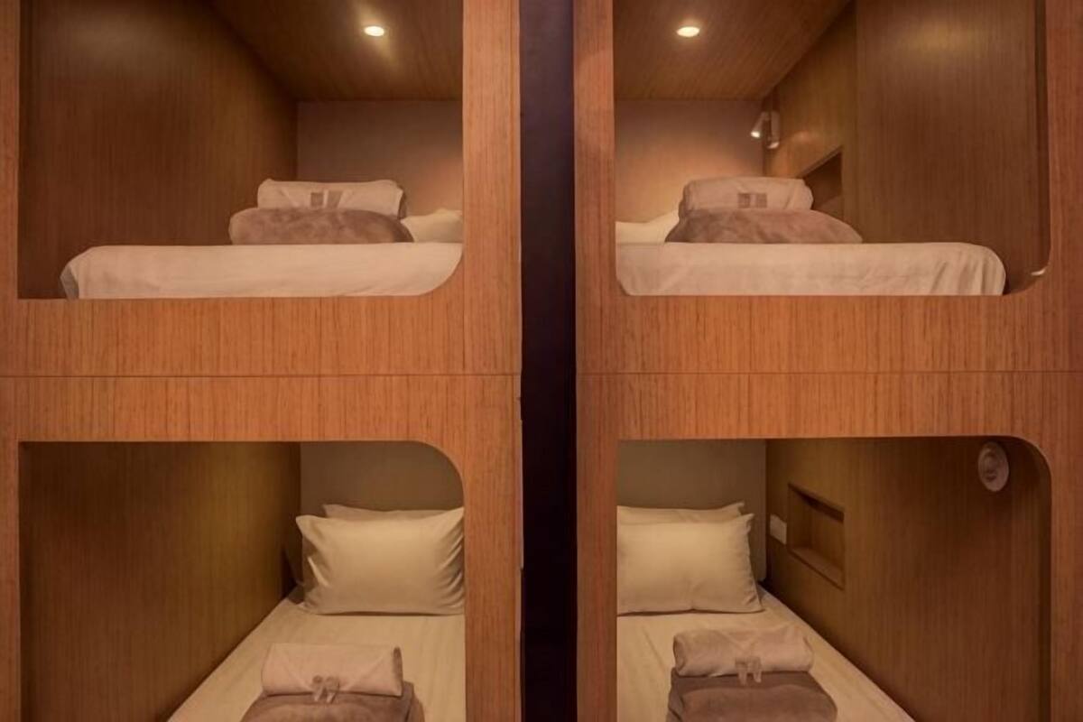 A room with bunk beds, wooden walls, and a small window.
