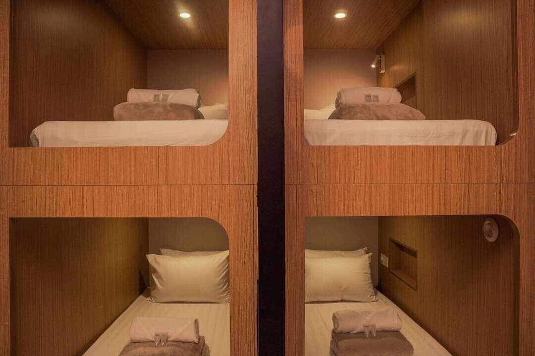 Una habitación con dos literas, paredes de madera y una columna central.