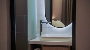 A bathroom with a white sink, a mirror, and a towel shelf. - Moonstar Cebu Hotel (Cebu City)