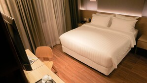 A hotel room with a large bed, a desk with a laptop, a chair, and a small table with cups and a pitcher. - Moonstar Cebu Hotel (Cebu City)