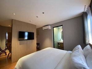 A modern hotel room with a large bed, a flat-screen TV mounted on the wall, and a bathroom visible through an open door. - Moonstar Cebu Hotel (Cebu City)